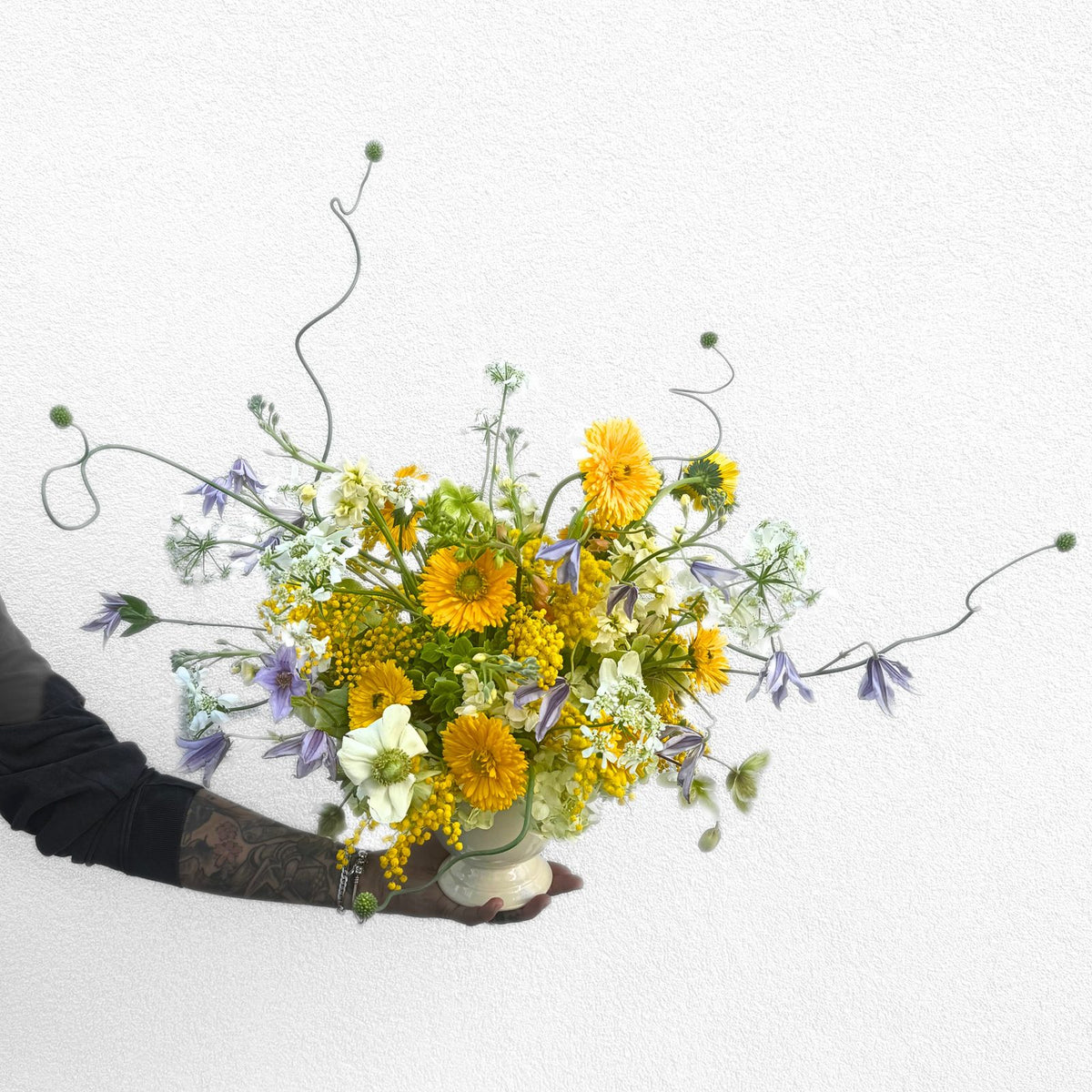 Bright golden-yellow get well arrangement of calendula, mimosa, white anemone and purple clematis, hand-designed by The Flower Bar in Larchmont, NY