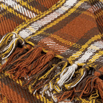 Close-up of woven textile with brown, gold, and white striped pattern and decorative fringe trim.