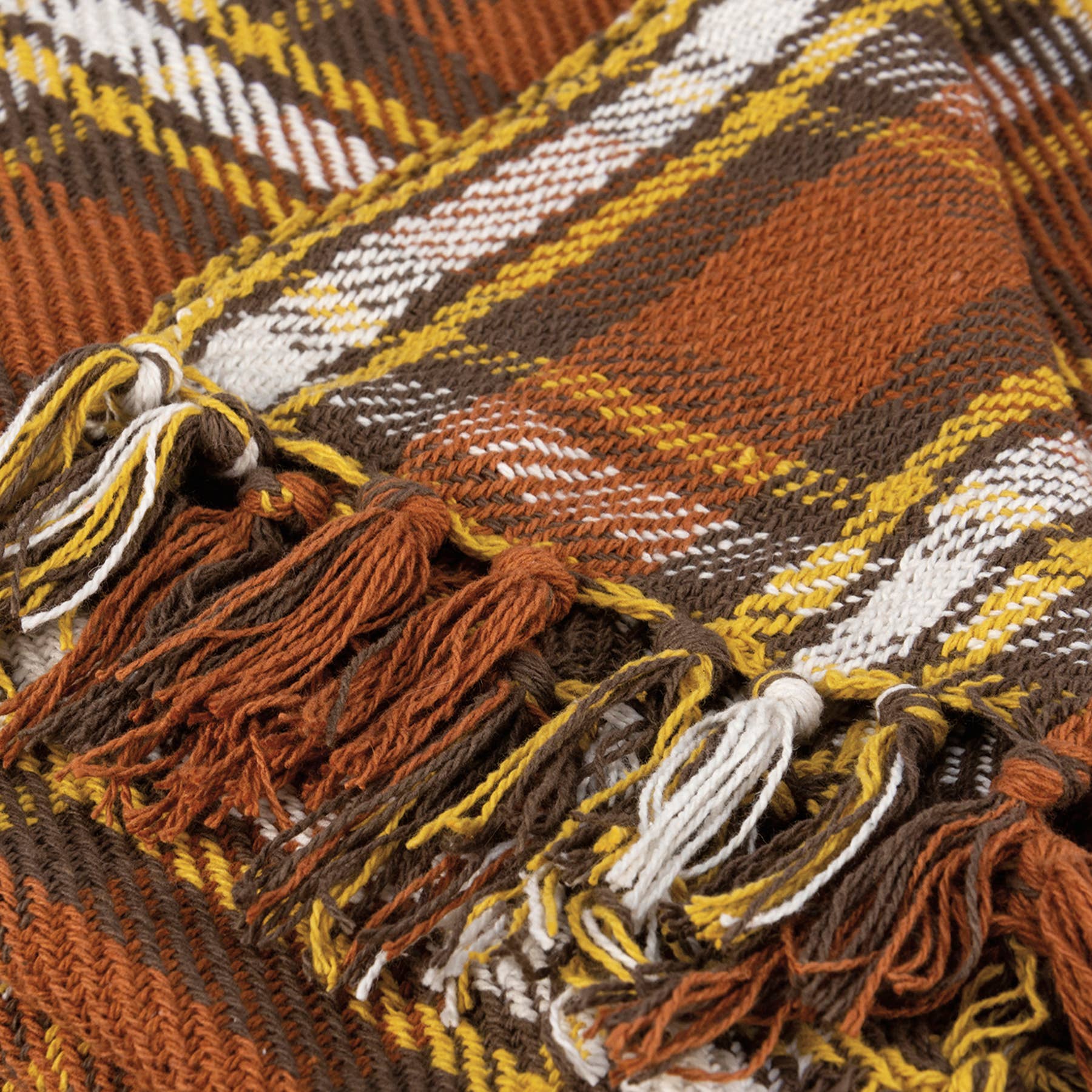 Close-up of woven textile with brown, gold, and white striped pattern and decorative fringe trim.