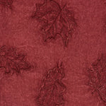 Deep burgundy fabric with embroidered floral motifs featuring delicate vine and leaf designs.
