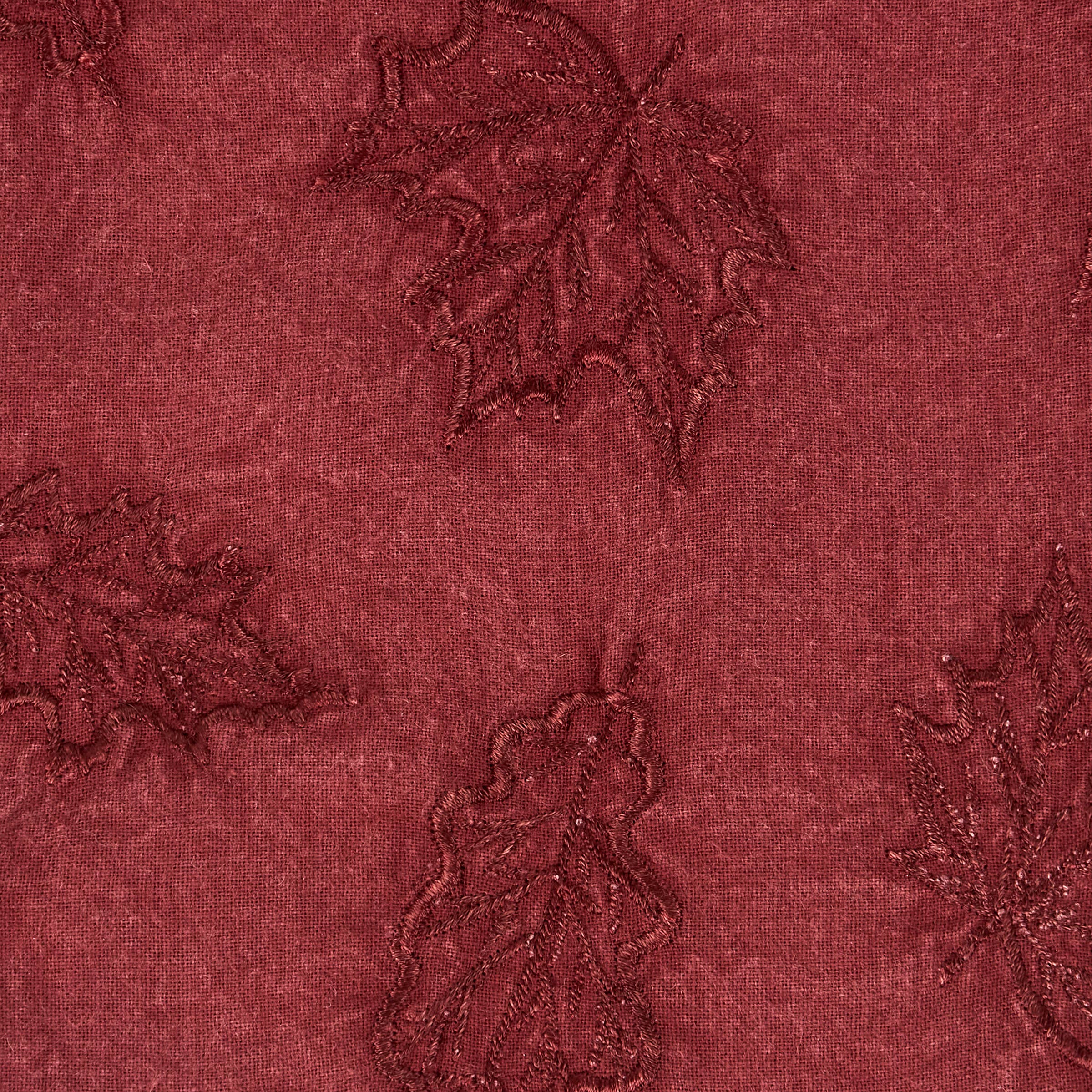 Deep burgundy fabric with embroidered floral motifs featuring delicate vine and leaf designs.