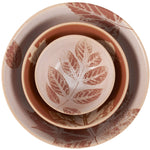 Nested ceramic bowls with rust-red leaf motifs in varying sizes, arranged concentrically on a white background.