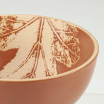 Terracotta ceramic bowl with pressed botanical branch design in rust tones.