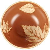 Terracotta bowl with cream-colored leaf etchings including maple and fern designs on a glossy brown ceramic surface.