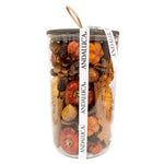 Clear cylindrical vase filled with dried flowers and botanicals in brown, orange, and red tones with an Andalucia branded ribbon.