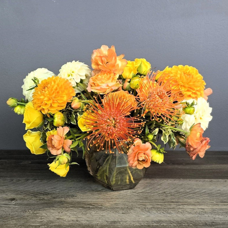 Flower arrangement with orange, yellow and white flowers.