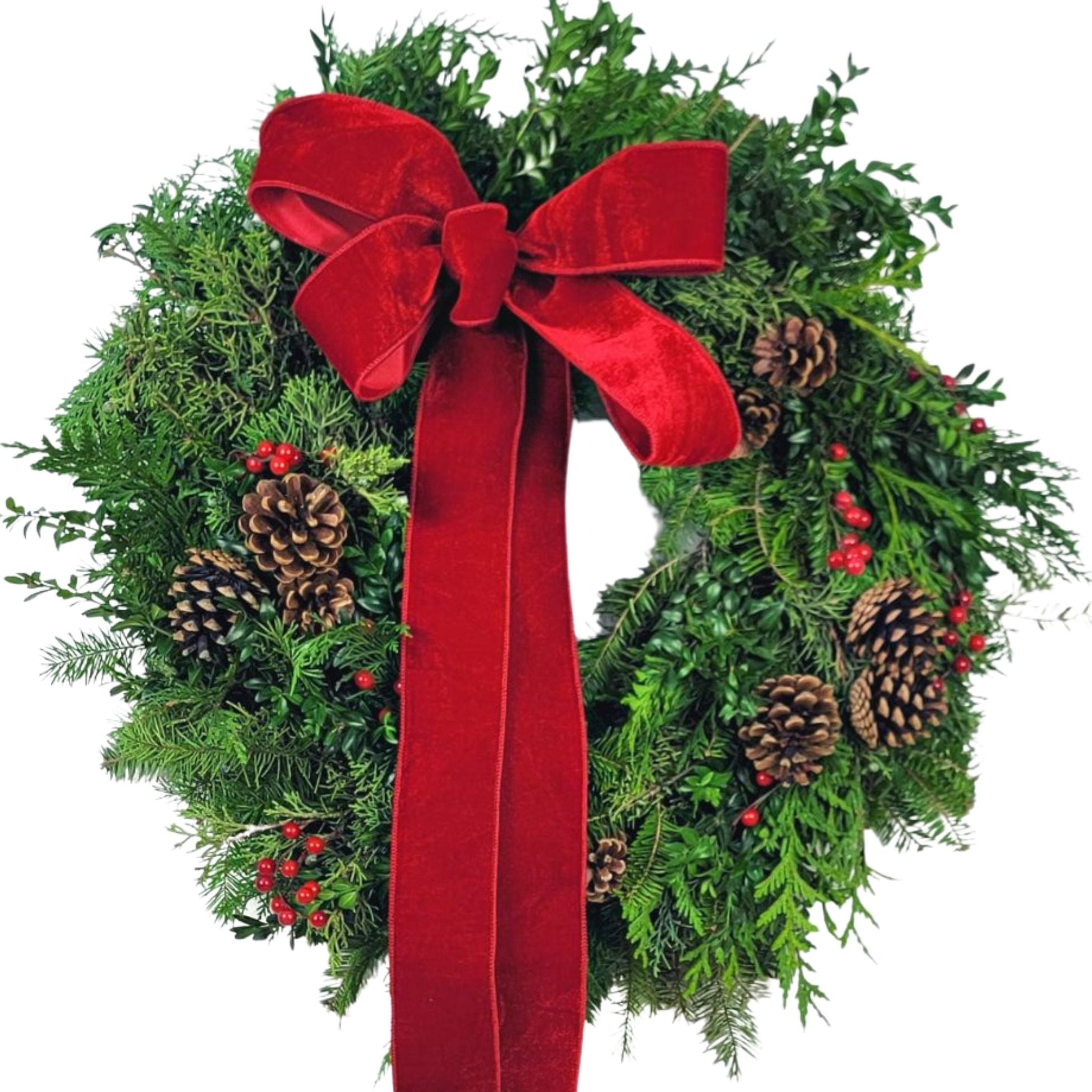 Lush evergreen wreath adorned with natural pinecones, red berries, and a bold red velvet bow.