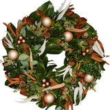 Festive evergreen wreath adorned with copper and gold ornaments, cinnamon sticks, pinecones, and white ribbon accents.