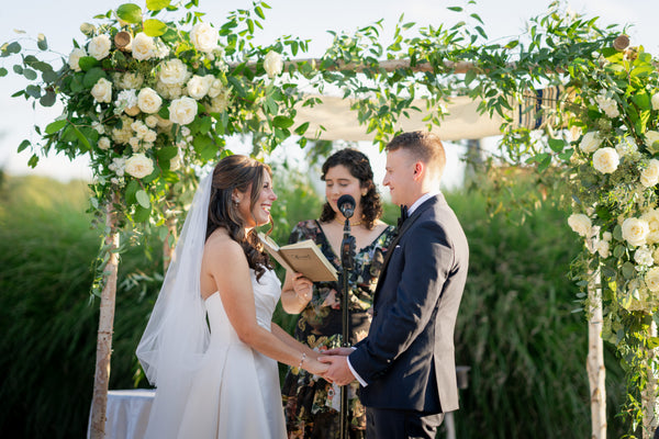 Wedding ceremony under a white floral arch by The Flower Bar, Larchmont NY