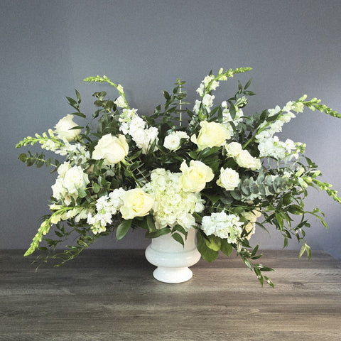 White roses, hydrangeas, and stock flowers with eucalyptus greenery in a pedestal vase arrangement. — The Flower Bar, Larchmont NY