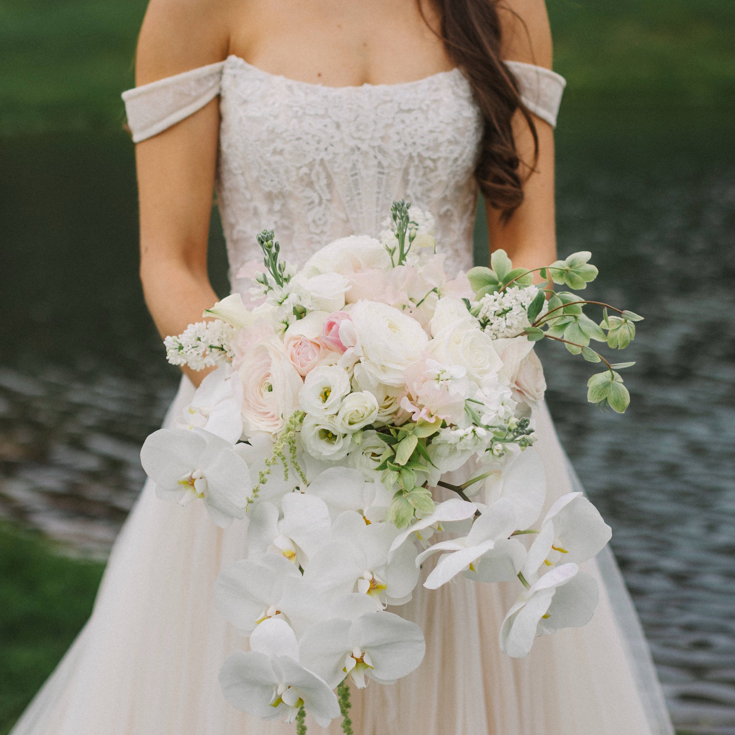 Bridal bouquet with cascading orchids, garden roses, and ranunculus by The Flower Bar, Larchmont NY wedding florist
