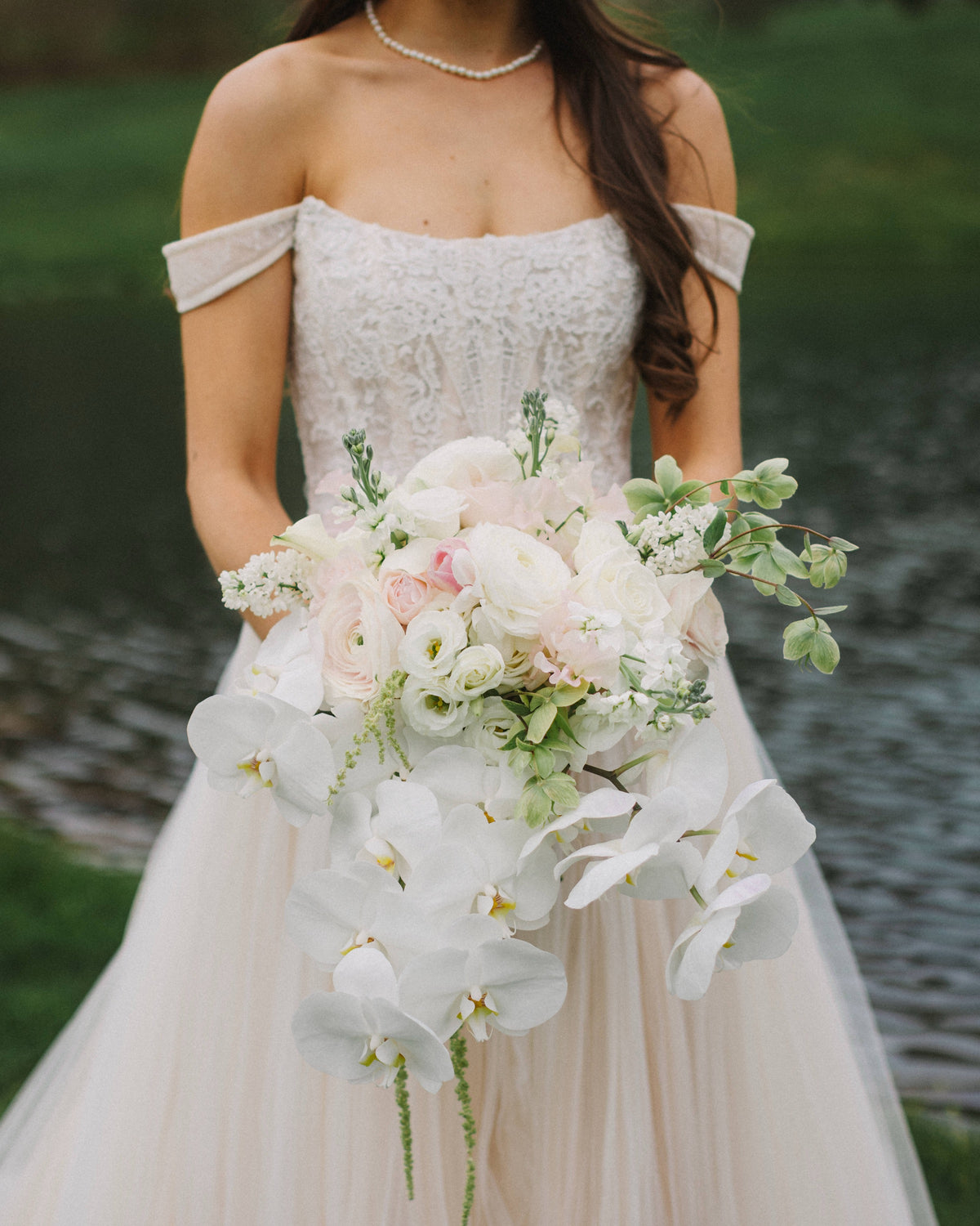 Bridal bouquet with cascading orchids, garden roses, and ranunculus by The Flower Bar, Larchmont NY wedding florist